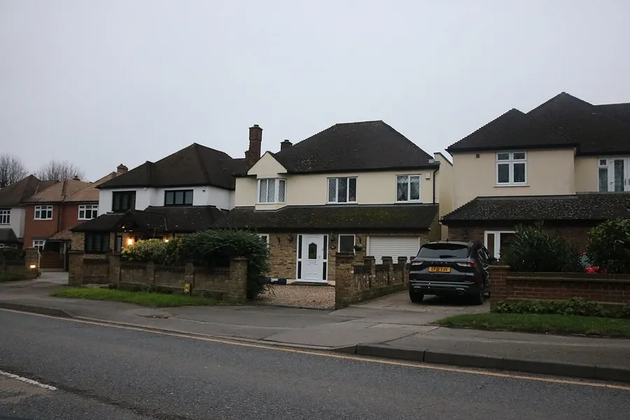 Detached houses with wide front driveways and brick boundary walls on Hall Lane in Upminster