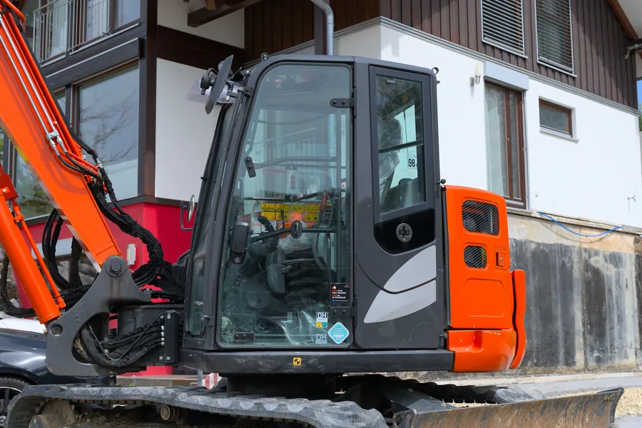 Mini digger parked close to a house ahead of excavation for a new sub-base