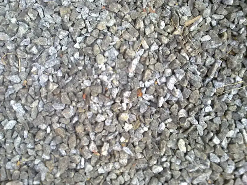 Grey crushed stone aggregate of the kind compacted in layers as the sub-base under a driveway
