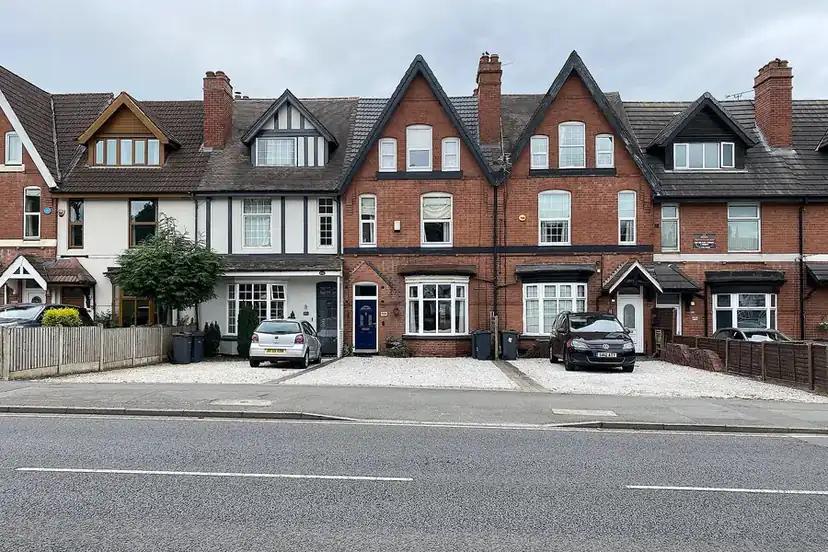 Front garden of a brick house with an old driveway surface partly removed before relaying
