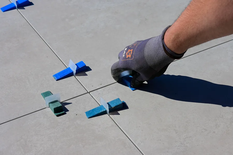 Close-up of large-format porcelain patio slabs being laid with tight joints on a mortar bed