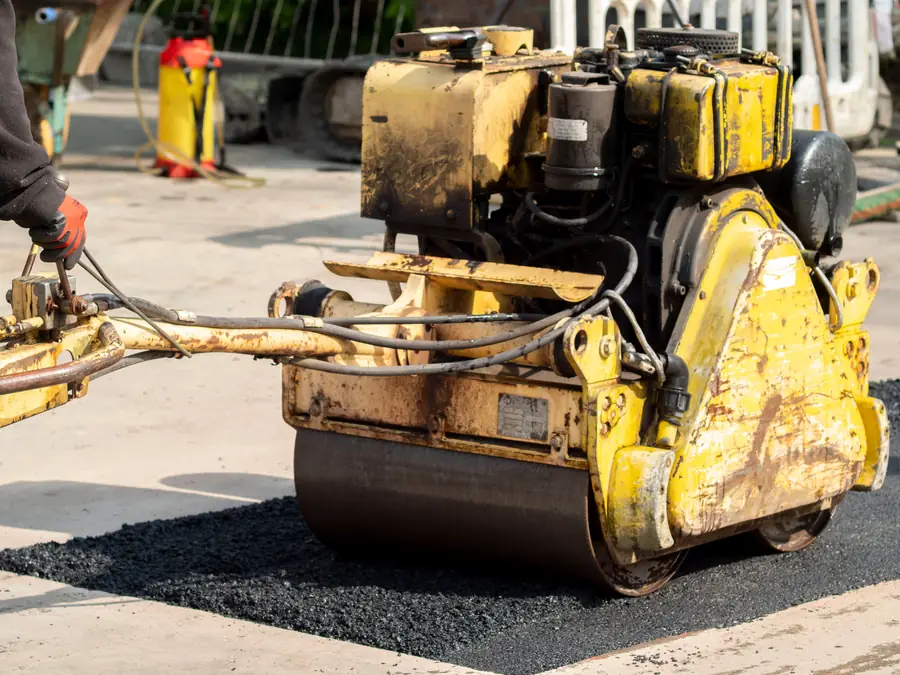 Close-up of a roller compacting freshly laid hot tarmac on a driveway surface
